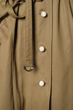 Görseli Galeri görüntüleyiciye yükleyin, Close-up of WAYT Studio Grotesk Dreams Khaki Trench Coat highlighting the metal D-ring belt and cream enamel buttons on khaki gabardine fabric.