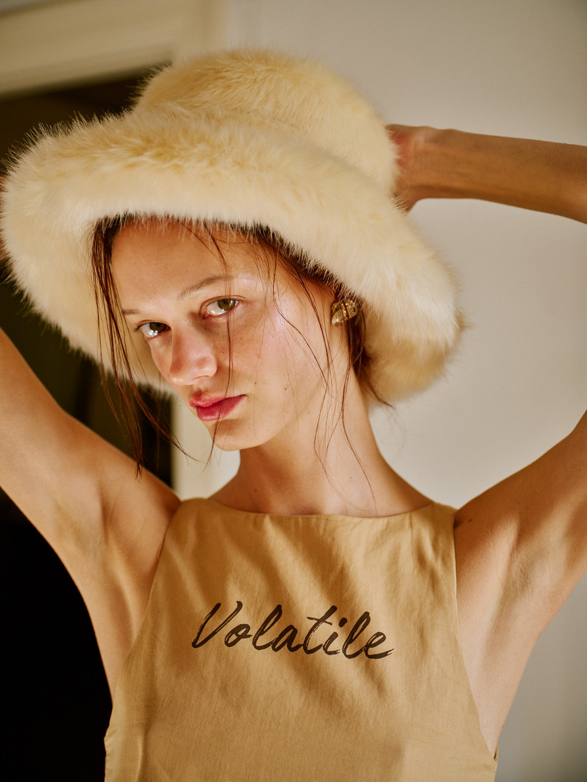 Modelin üzerinde WAYT Studio tasarımı krem rengi Polunin suni kürk şapka yer alıyor. Yumuşak dokulu ve hacimli formuyla öne çıkan bu aksesuar, kış stiline retro bir zarafet katıyor. Moda portre çekiminde doğal saç ve makyaj ile tamamlanmış.